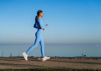A woman walks along a waterside path.