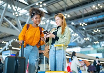 Two women stand in an airport.