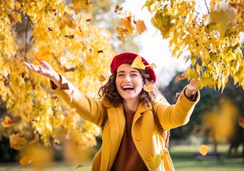 A woman throws leaves in the air.