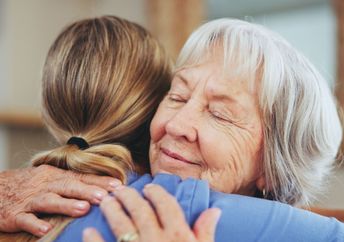 A woman hugs another woman.