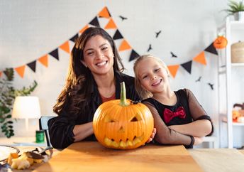 A mother and daughter proudly display their carved jack-o'-lantern.