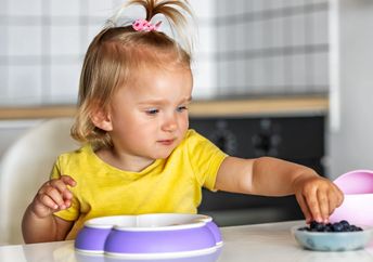 Toddler eating blueberries.