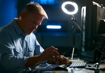 A retired man refurbishes a laptop.