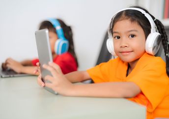 Two young students wear headphones.
