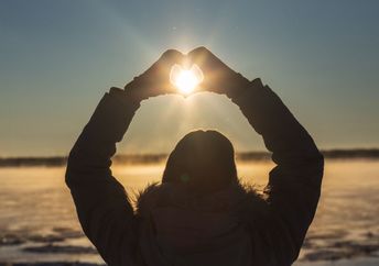A woman makes a heart with her hands.