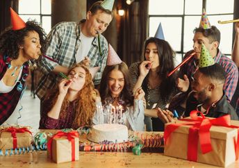 A group of friends celebrate together around a cake.