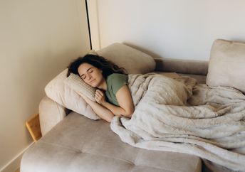 A woman rests peacefully under a warm blanket.