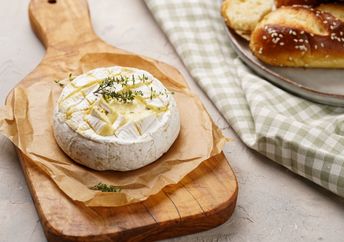 Oven baked camembert cheese on wooden board.