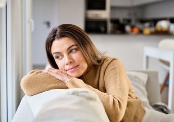 A woman sits on a sofa.