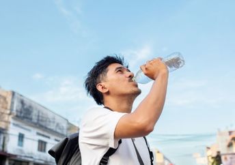 Young man drinking water from a plastic bottle.