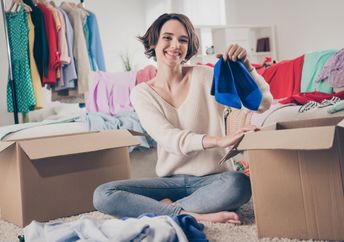 A woman holds up a pair of shoes.