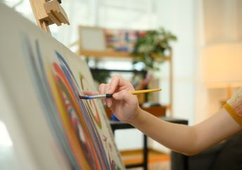 A close up of a female artist painting abstract artwork.