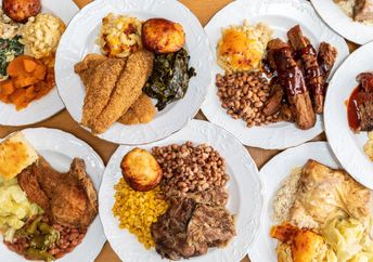 A soul food feast with a variety of dishes served on numerous plates.