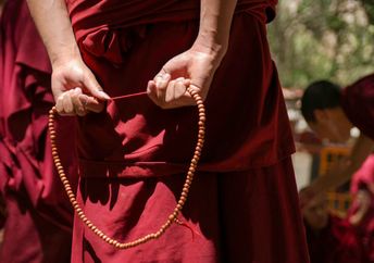 Tibetan Buddhist Monk with his red robe and prayer beads.