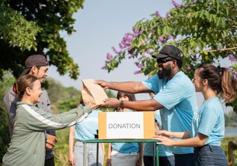 A team of volunteers with a donation box outdoors.
