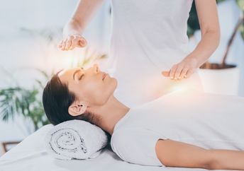 A calm woman receives reiki healing therapy.