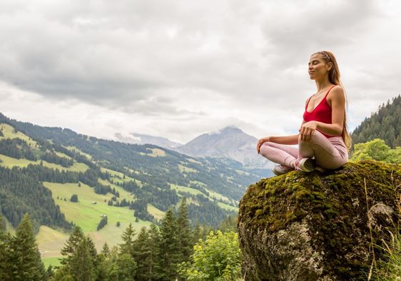 A woman meditates on a mountain.