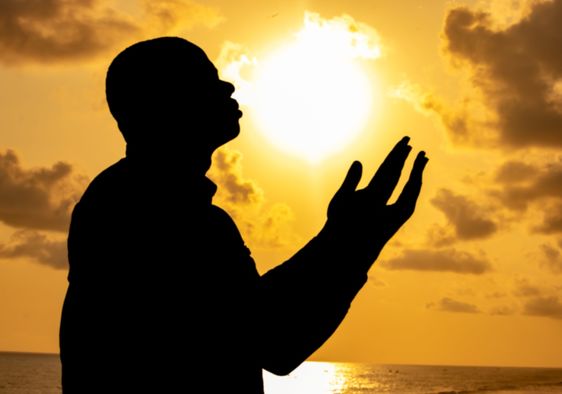 A man silhouetted against a colorful sunset.