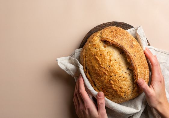 A person holds a loaf of sourdough bread.