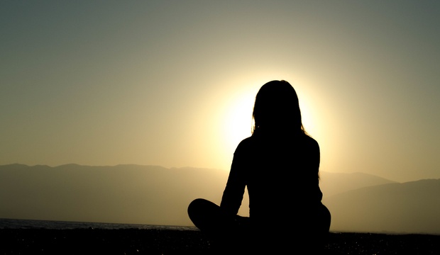 Woman meditating at sunset