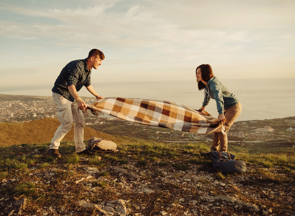 Couple laying blanket down for picnic