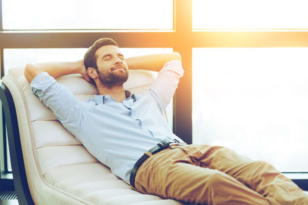 Time to relax. Handsome young man holding hands behind head while sleeping on the couch