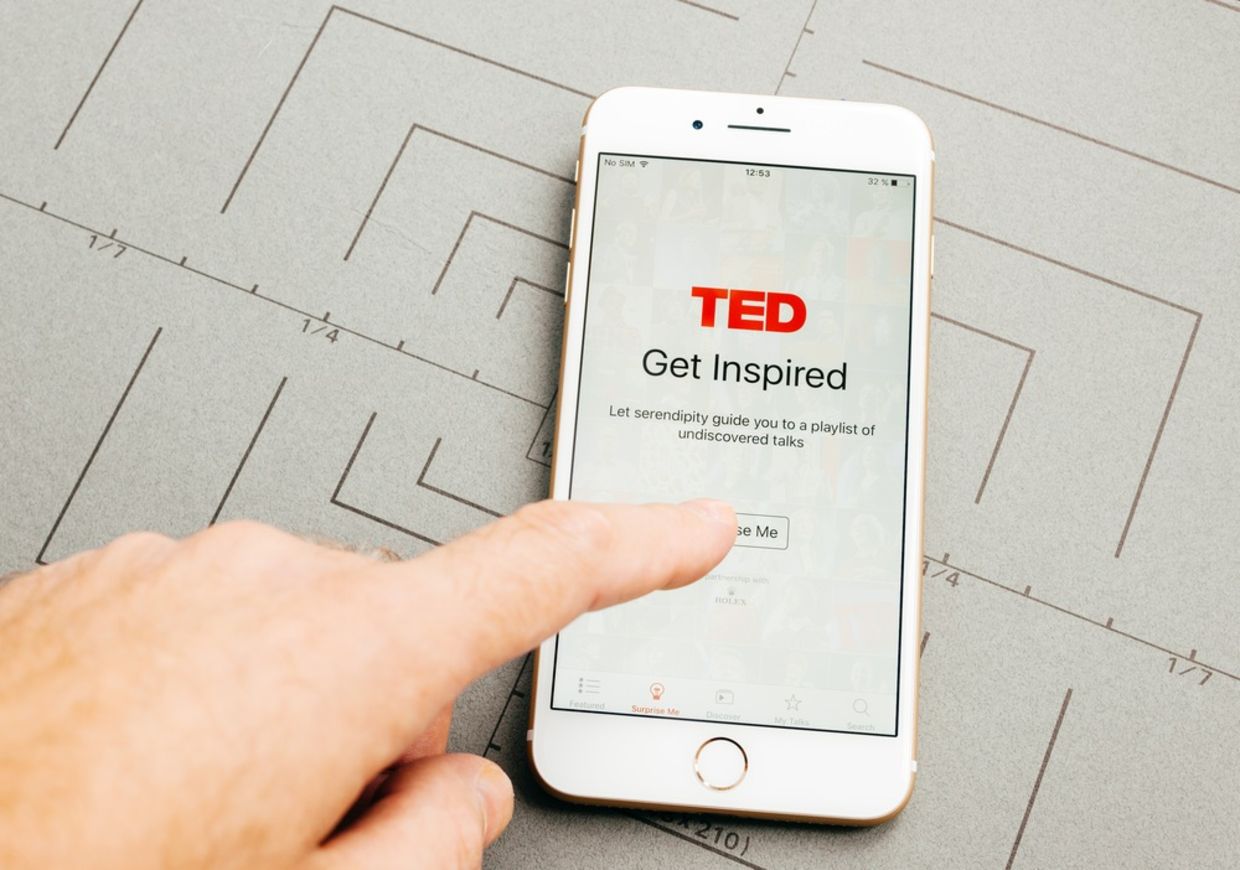 Male hand holding New Apple iPhone 7 Plus after unboxing and testing by installing the app application software TED speaking media app