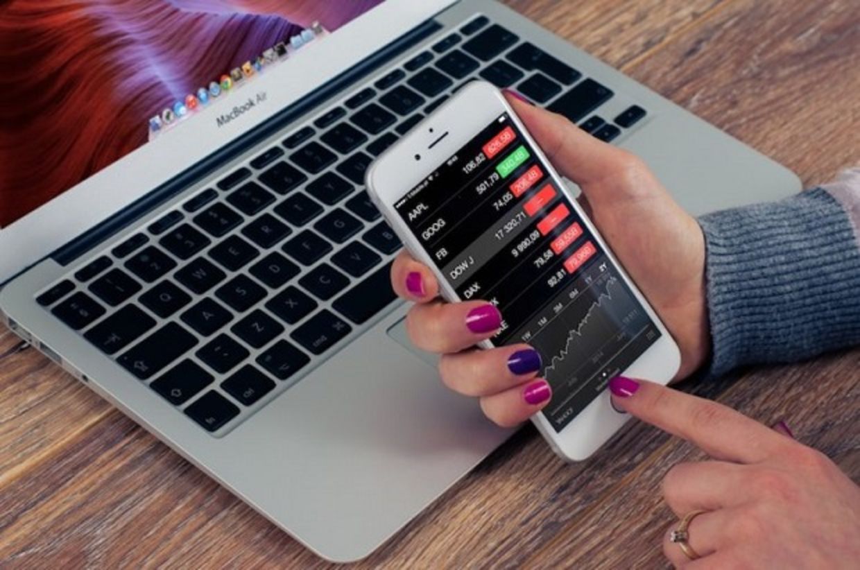 A woman checks a financial app on her iPhone