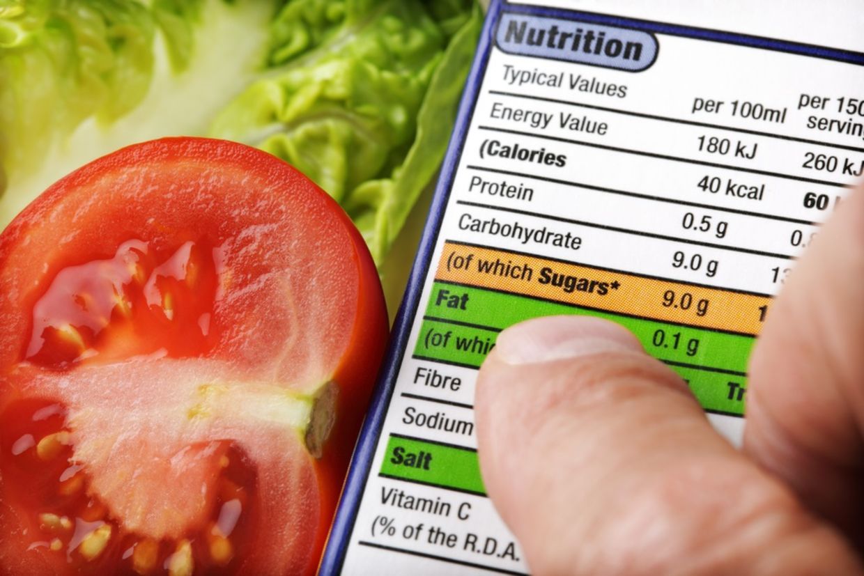 Reading a nutrition label on food packaging with fresh salad background