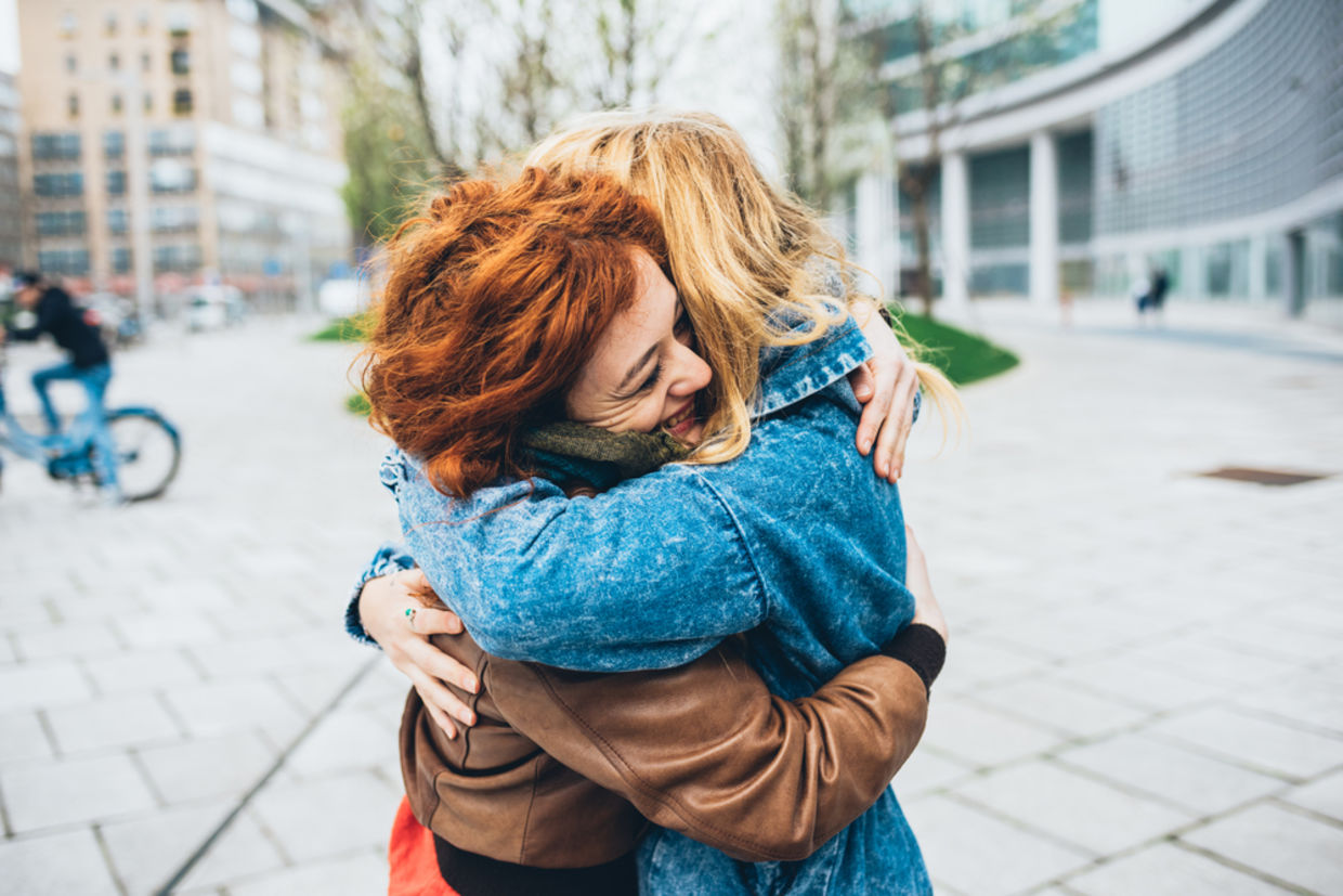 Two friends meeting in the street of the city and hugging