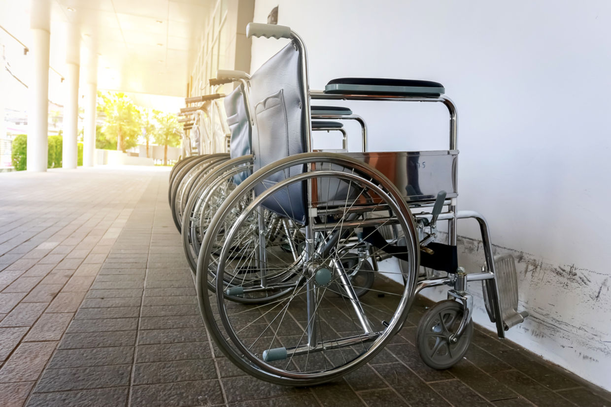 A row of wheelchairs stands next to a wall