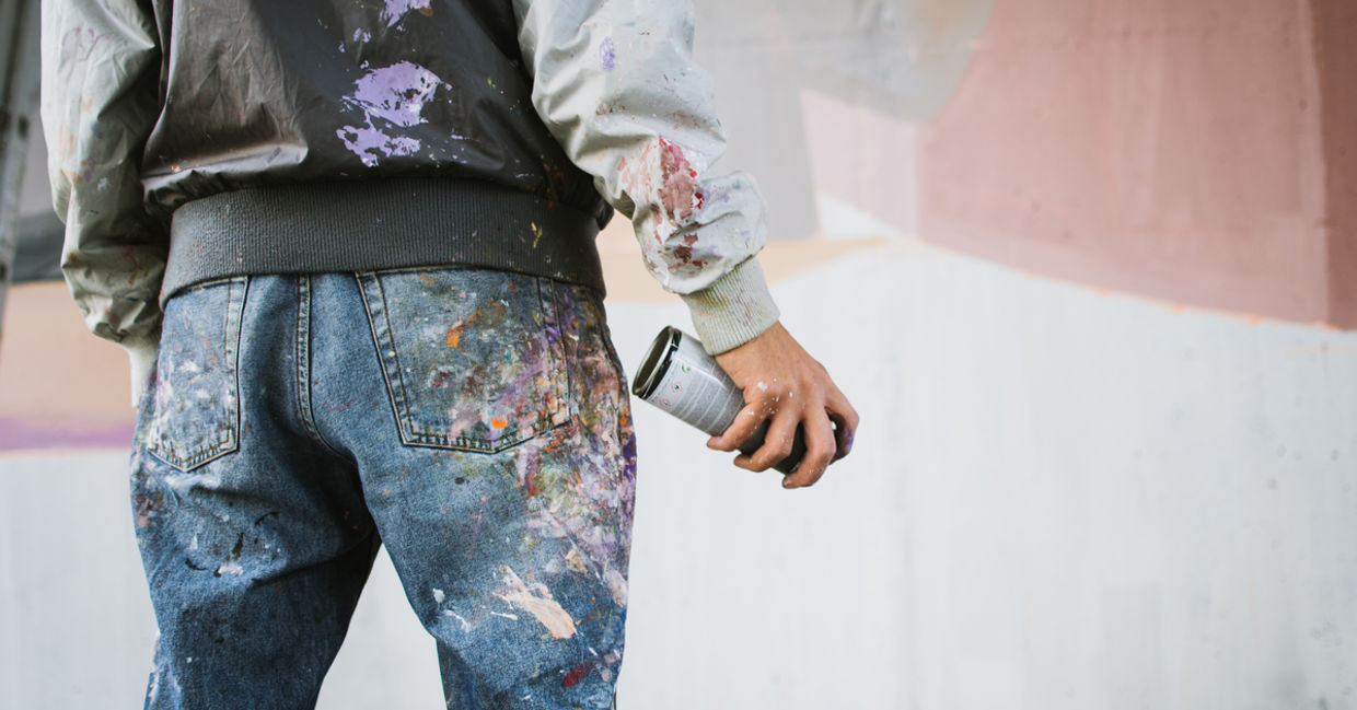 Graffiti artist with aerosol spray bottle near the wall