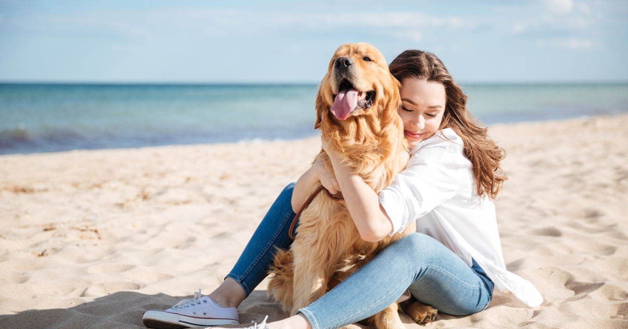 Woman sitting with dog on beach