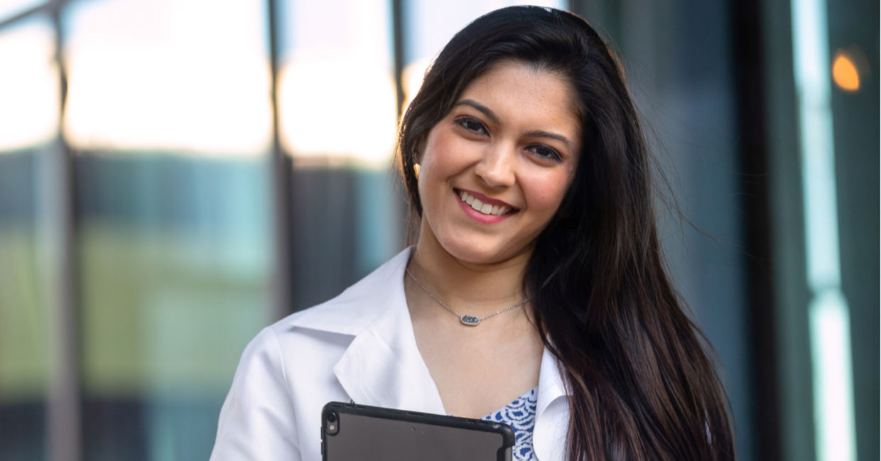 Native American student wearing a white hospital coat.