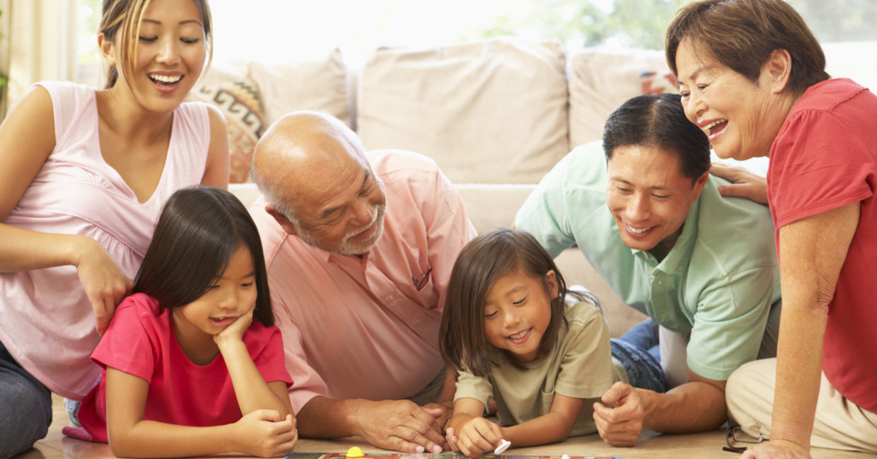 A family laughs while playing a board game.