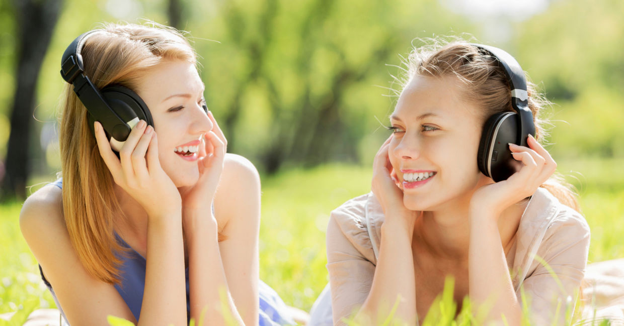 Two friends listen to music on headphones