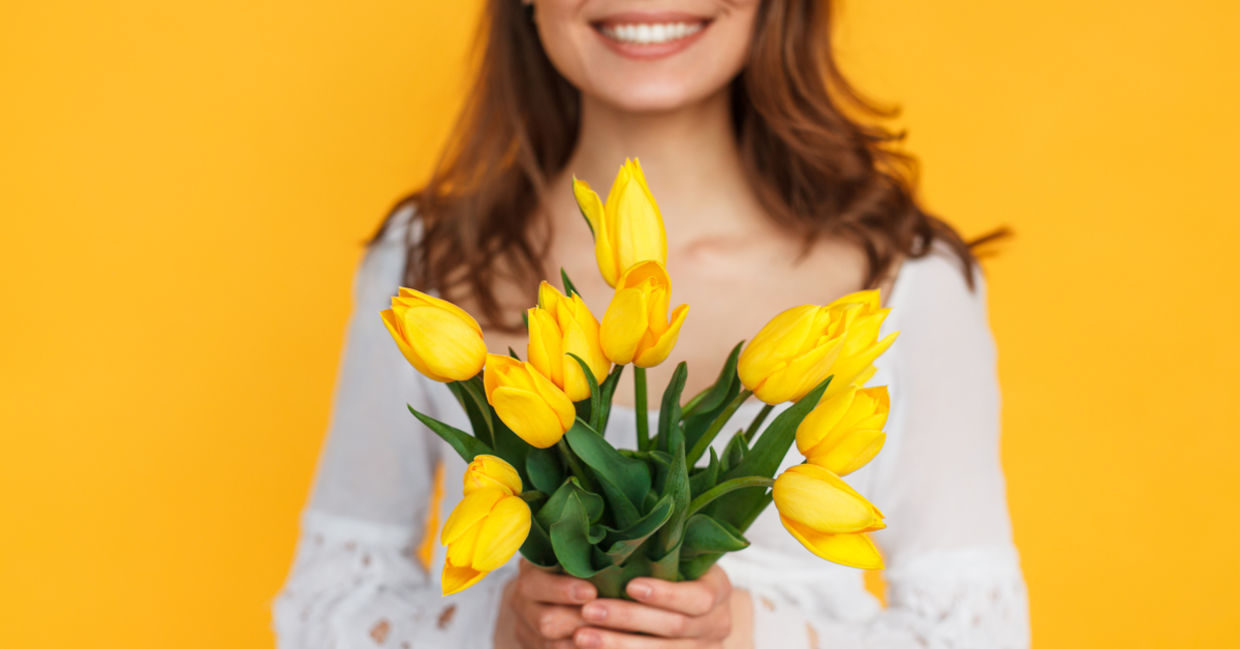 Photo of happy woman holding flowers to illustrate kindness