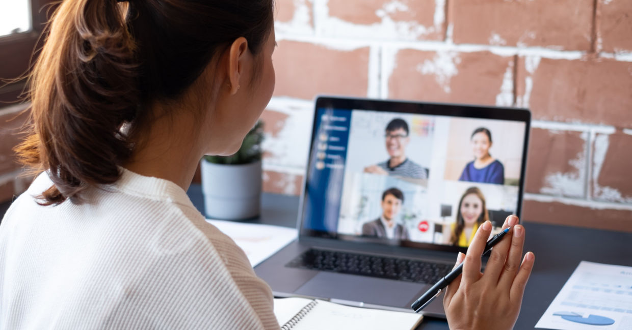 Female worker participating in remote video meeting with colleagues