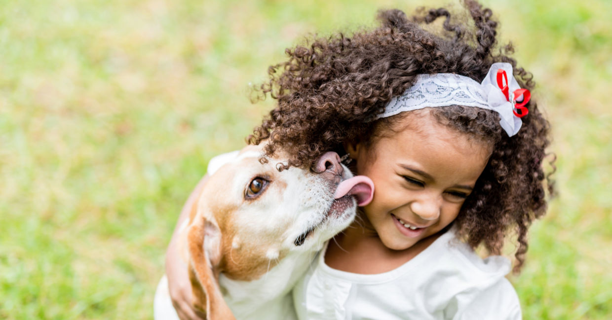 Girl being licked by her pet dog.