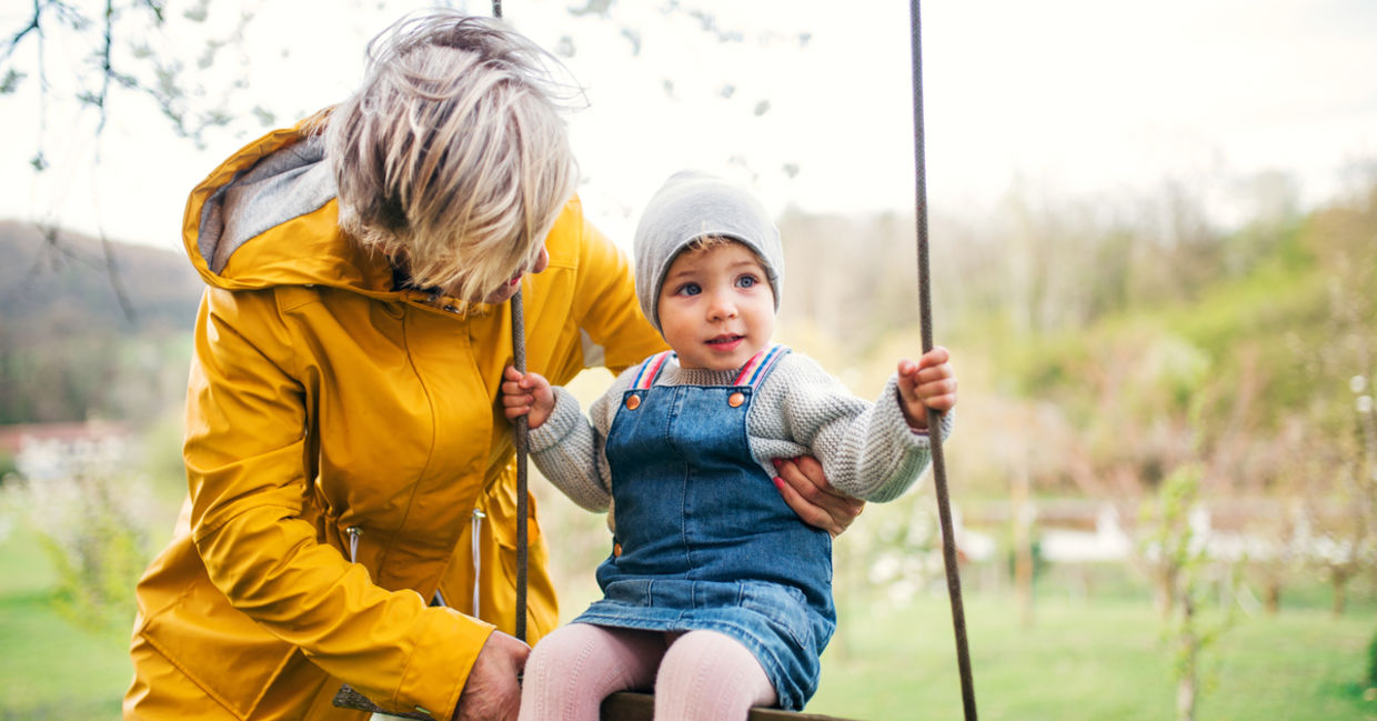 Grandmother helping a little kid on a swing