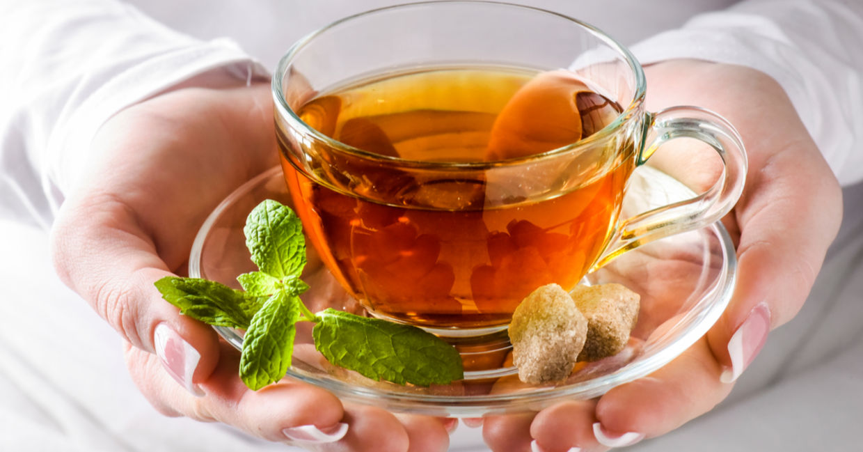 A woman holding a cup of headache soothing tea.