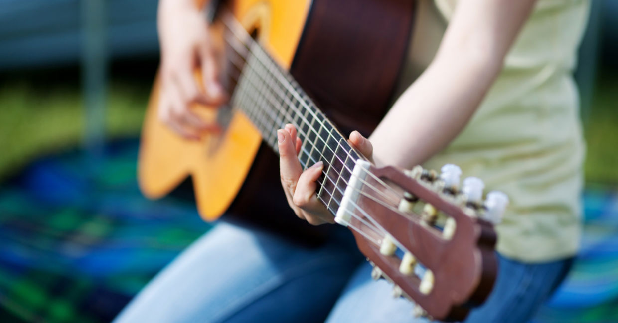 Girl learning how to play a guitar.