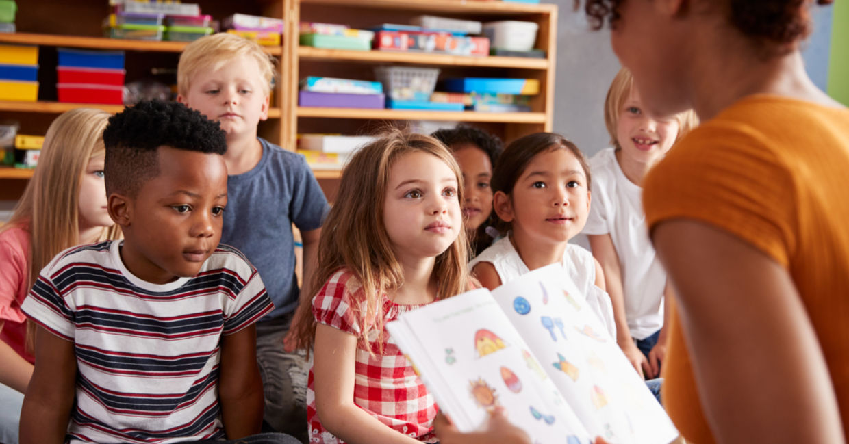 A teacher reads a story to young students.