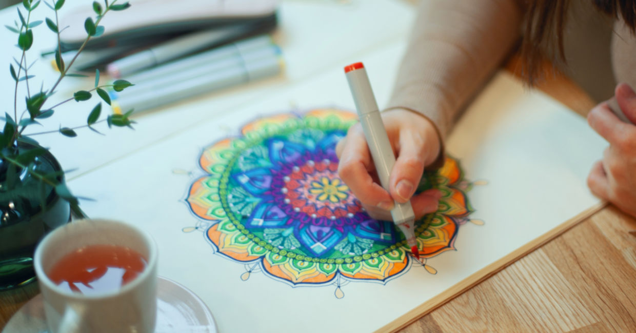 A woman draws a mandala.