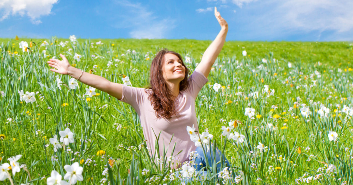 Happy woman sitting in a field of daffodils.