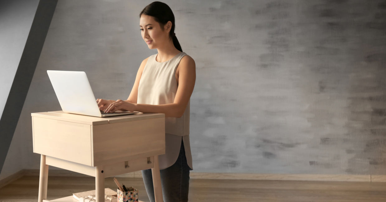 Woman typing on laptop at stand-up workplace