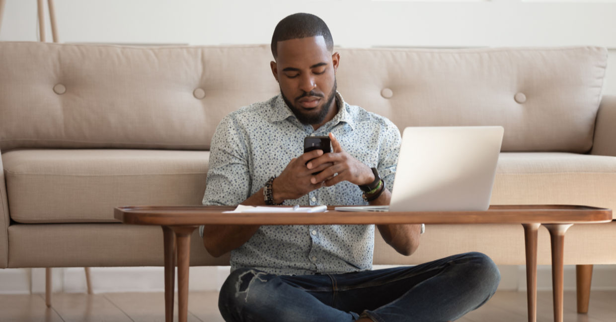 Man working leaned on couch cross-legged near coffee table