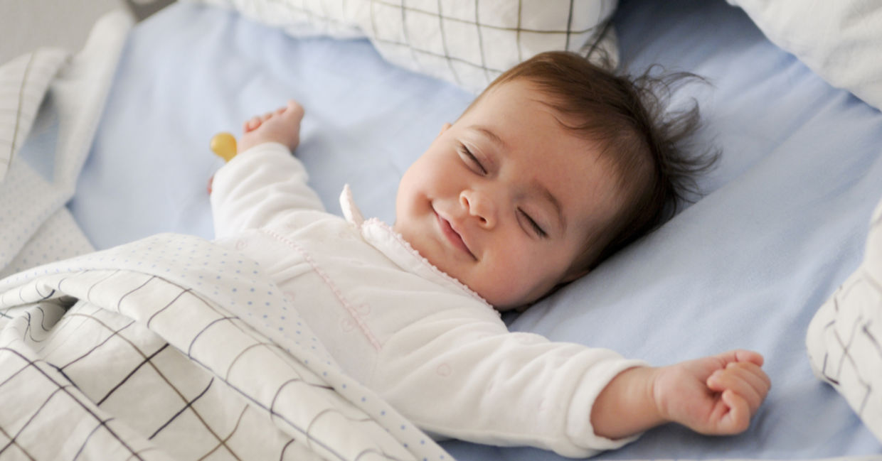 Smiling baby lying on a bed sleeping