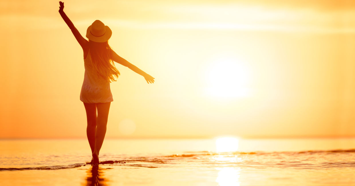 Woman walking on the beach at sunset.