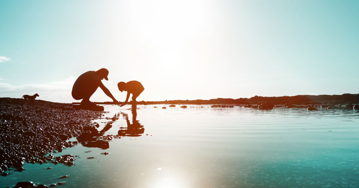 Silhouette of father and son playing on the beach at sunset